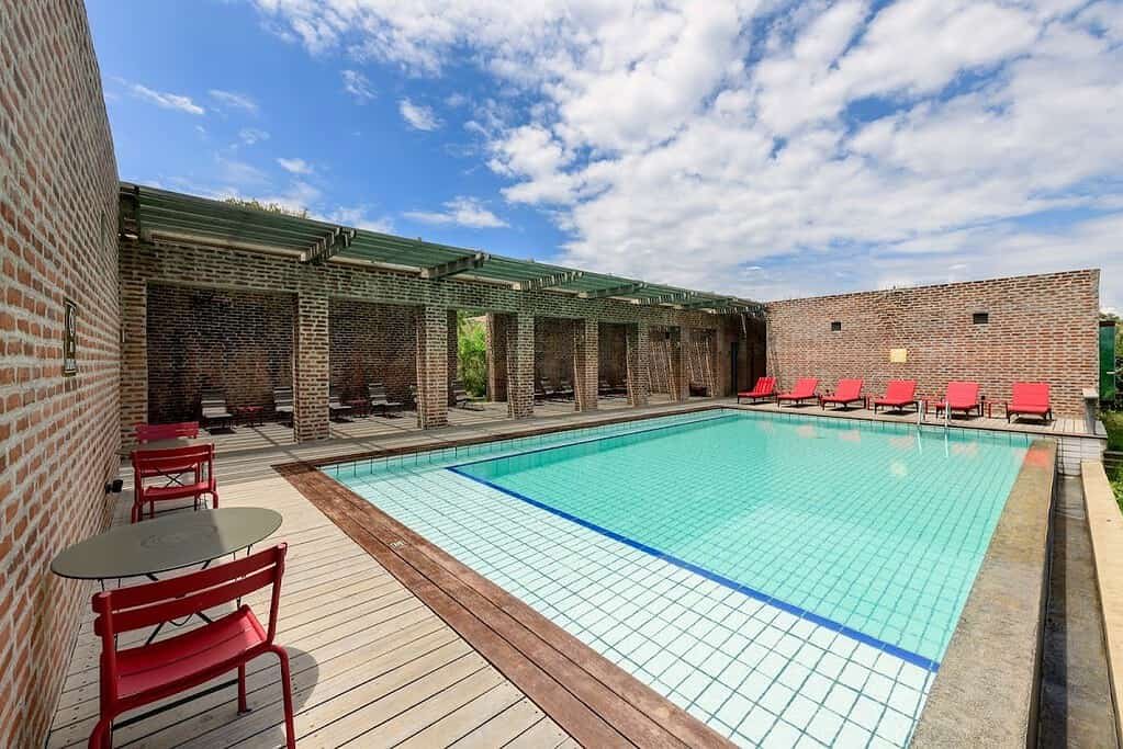 Ultra-luxury camps and lodges in the Maasai Mara 3 Swimming pool surrounded by a terrace, stone buildings and red sun loungers