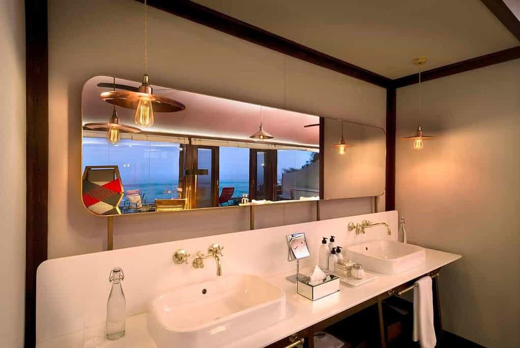 Ultra-luxury camps and lodges in the Maasai Mara 2 Safari-suite bathroom with basins, a broad mirror and views through glass doors
