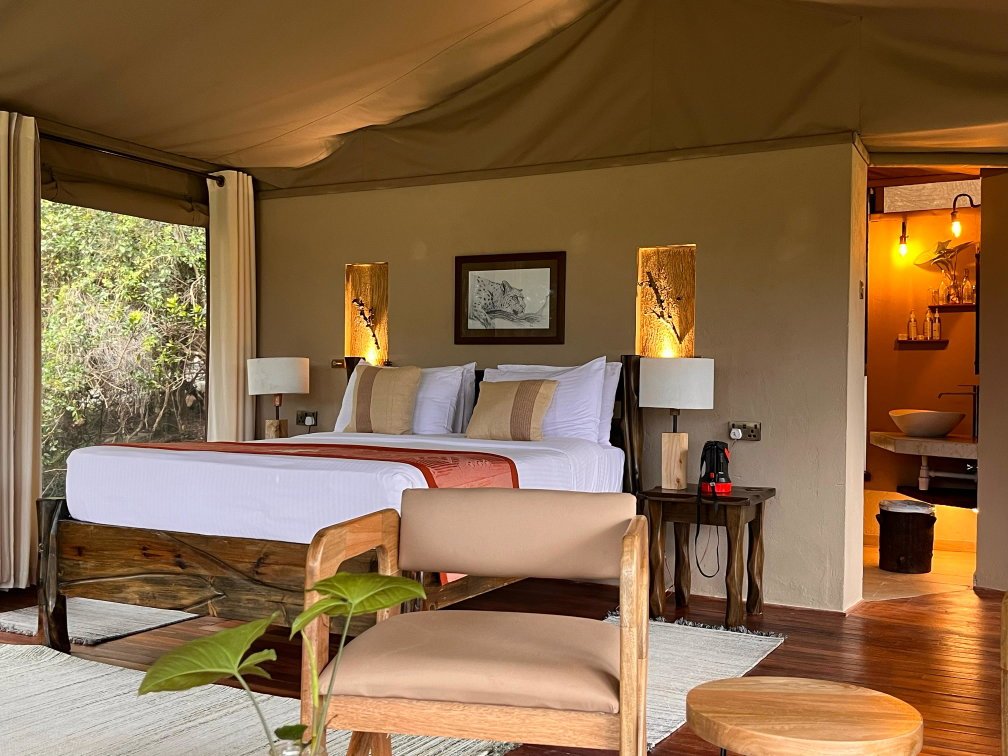 Ashnil Mara Camp modern tent bedroom with a lounge chair and hardwood floor