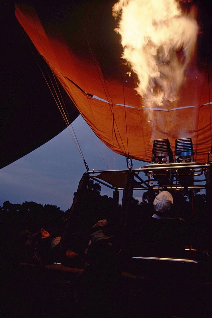 Burner flames rising into the fabric of a hot air balloon above its basket