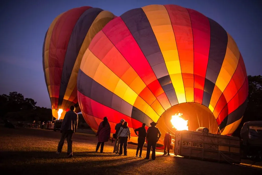 maasai mara balloon safari: People watching brightly coloured balloons being inflated before dawn