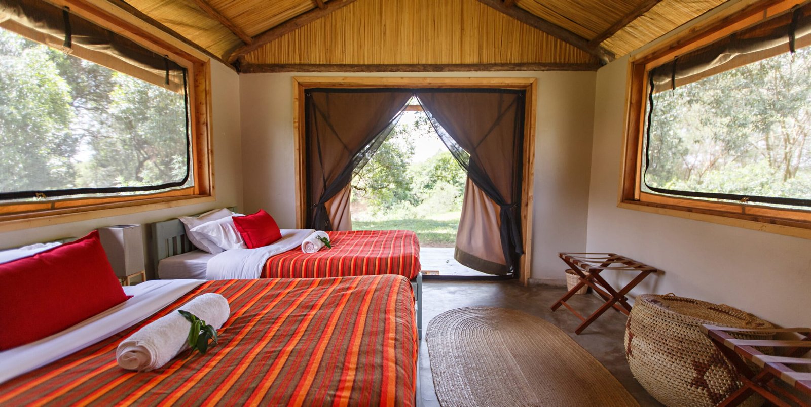 Twin beds and thatched roof inside an ensuite Wild Bandas room