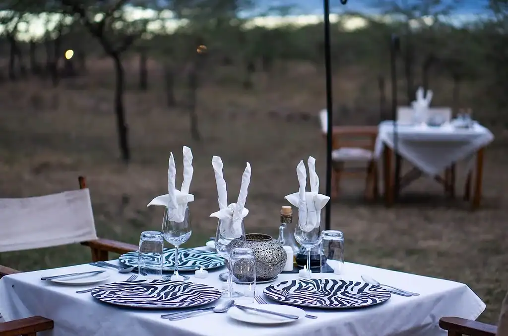 Bush dining in the Maasai Mara: breakfast, dinner and sundowners 3 Outdoor dining table set with glasses, folded napkins and a lantern