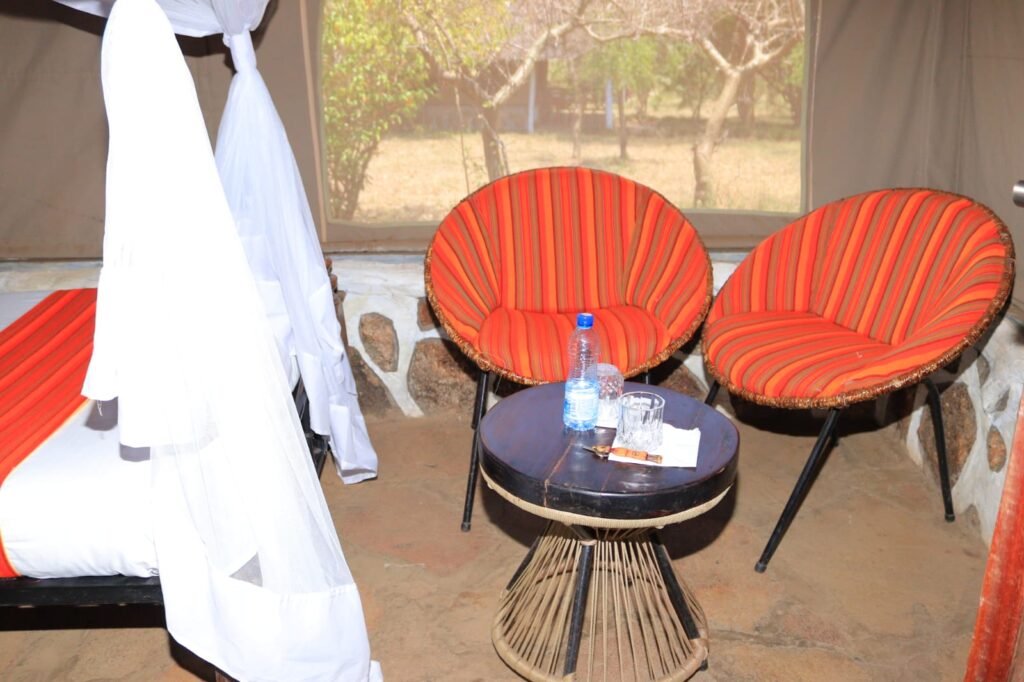 Elangata Olerai guest accommodation with red striped chairs, a round table and mosquito-netted bed