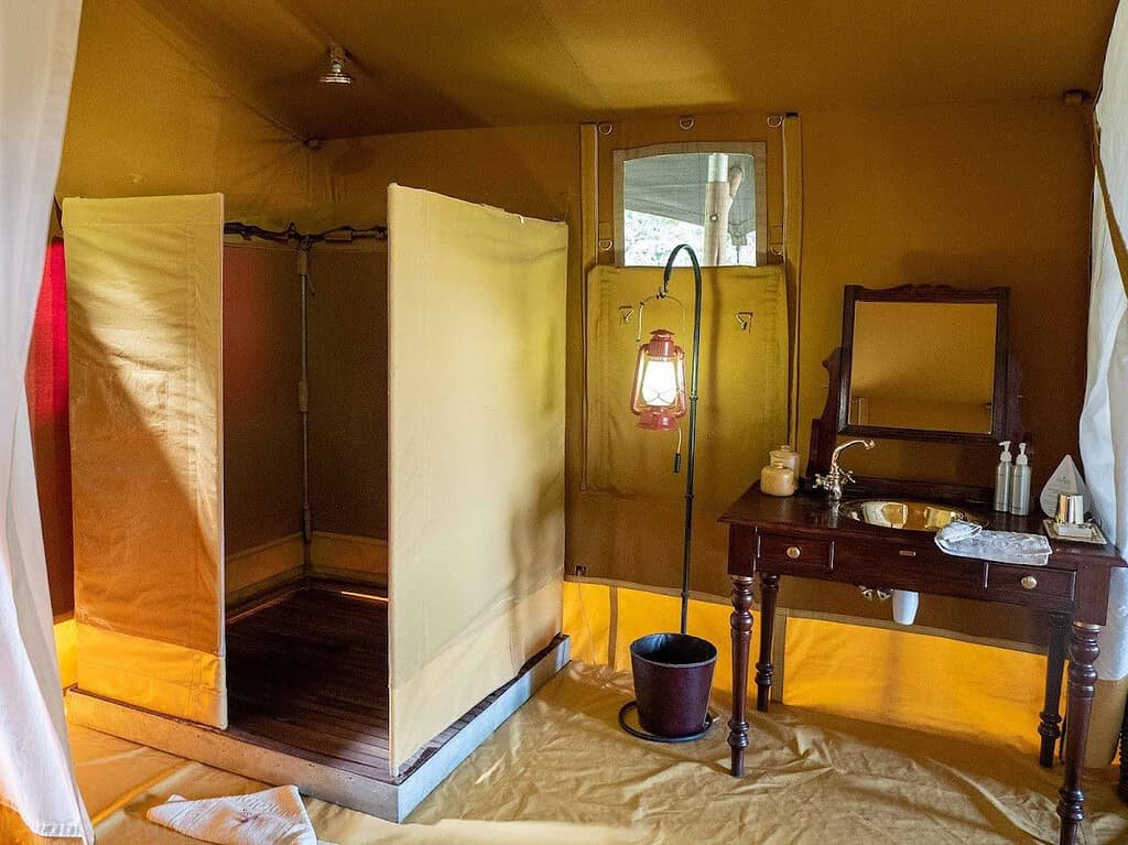 Canvas shower and wooden washstand in an Elephant Pepper Camp Safari Tent