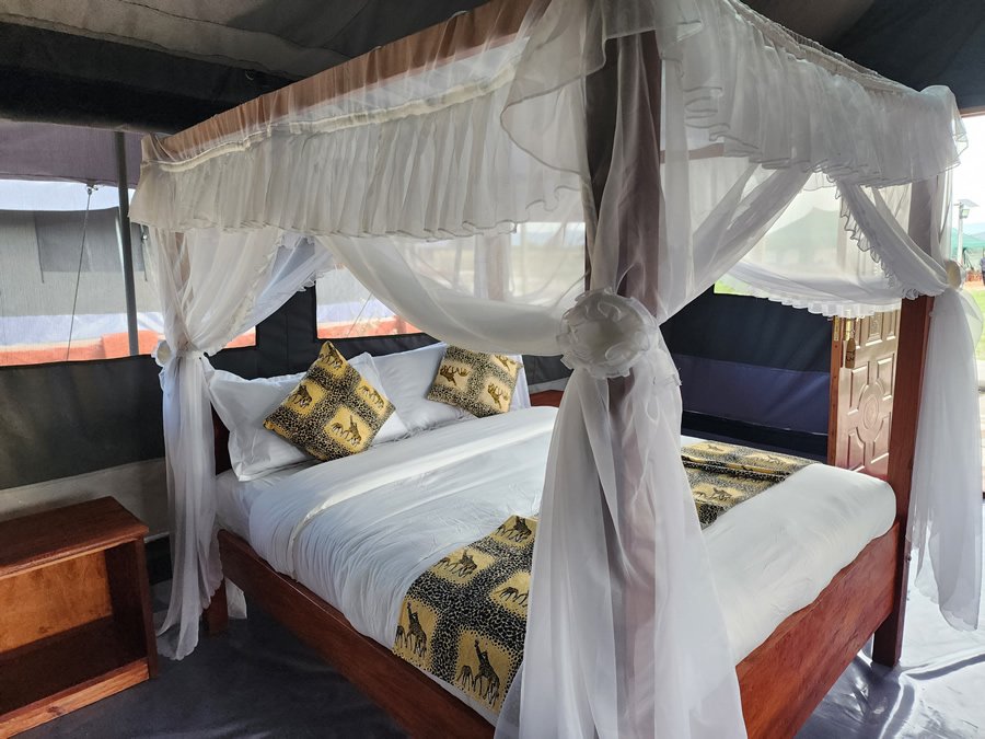 Maasai Mara lodges and camps 18 Endeem Mara Resort canvas bedroom with a wooden canopy bed and mosquito net