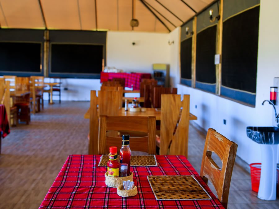 Endeem Mara Resort communal dining room with wooden chairs and red checkered tablecloths