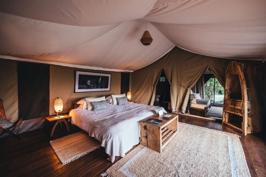 Enkewa Camp double-tent bedroom with a wooden floor and screened canvas walls