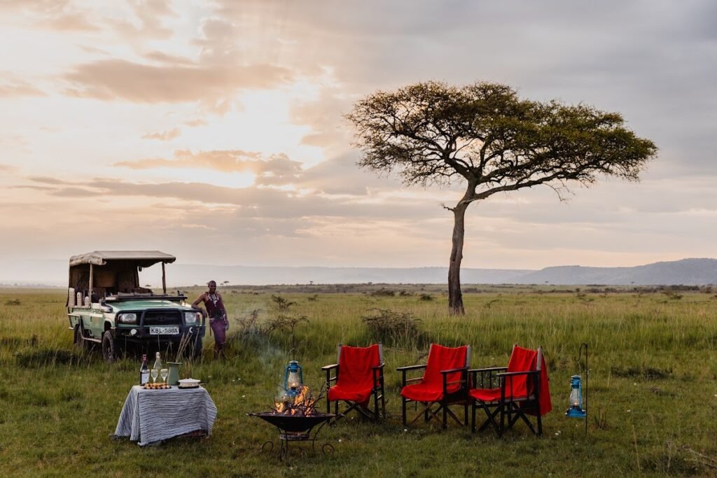 Enkusero Mara sundowner setup with red chairs beside a safari vehicle