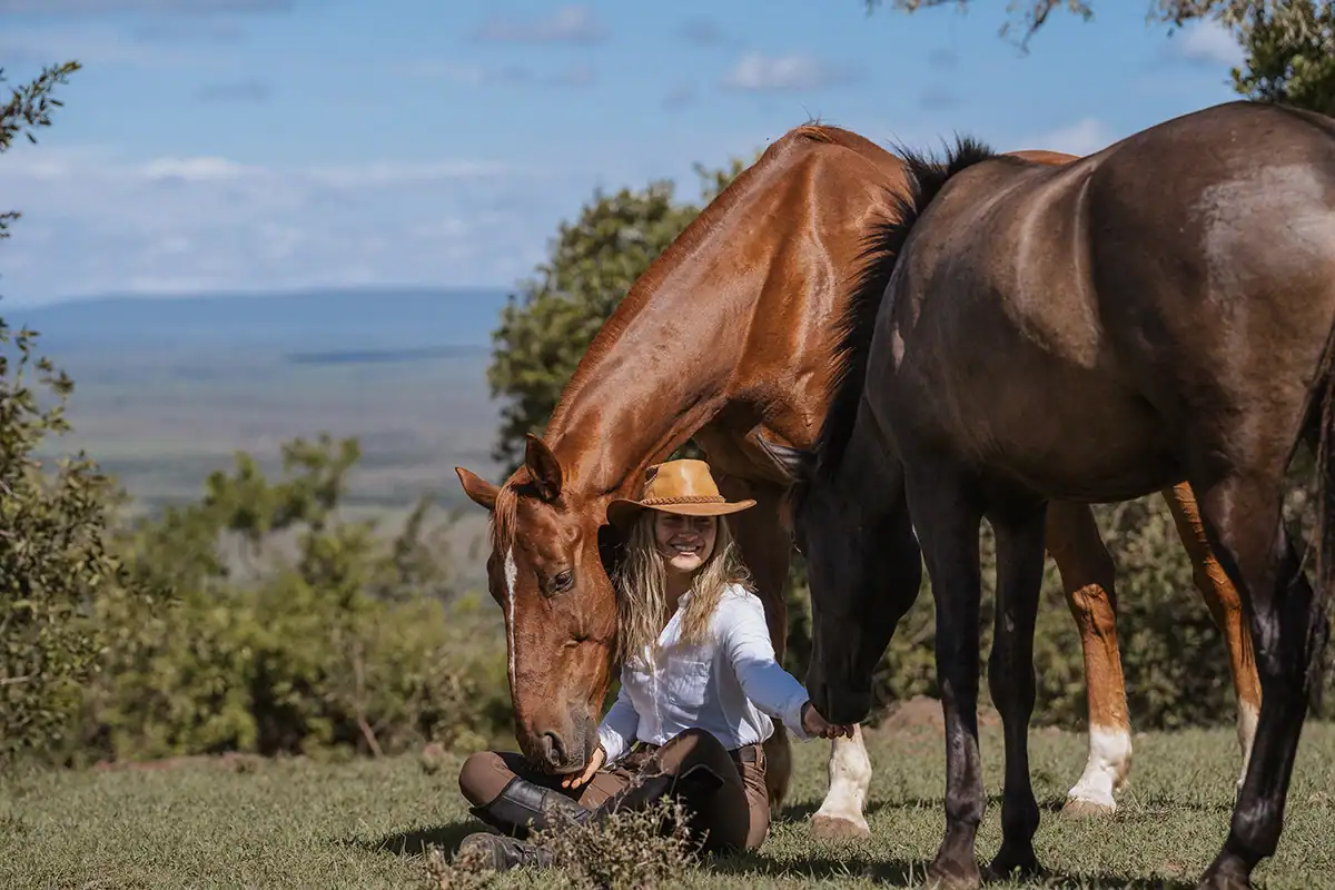 Horseback safaris in the Maasai Mara 1 Two horses beside a seated visitor, illustrating preparation for horseback safaris