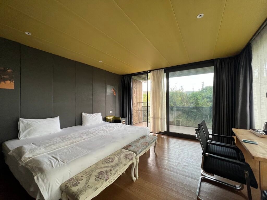 Jambo Mara Safari Lodge glass-cottage bedroom with a large window and wooden floor