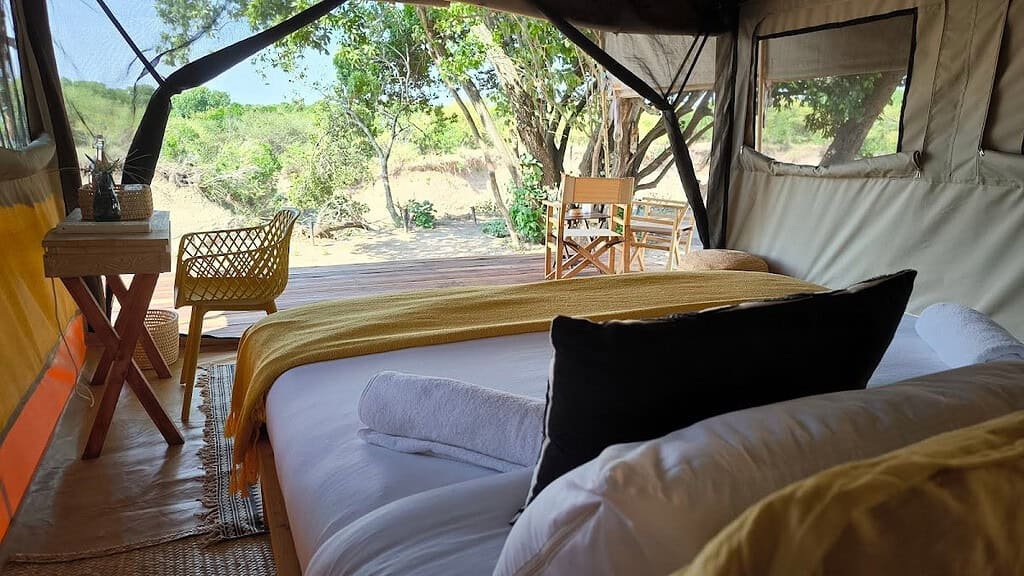 Canvas bedroom with a double bed beside a shaded outdoor seating area