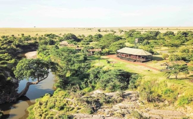 Aerial view of a safari camp and trees beside a winding river