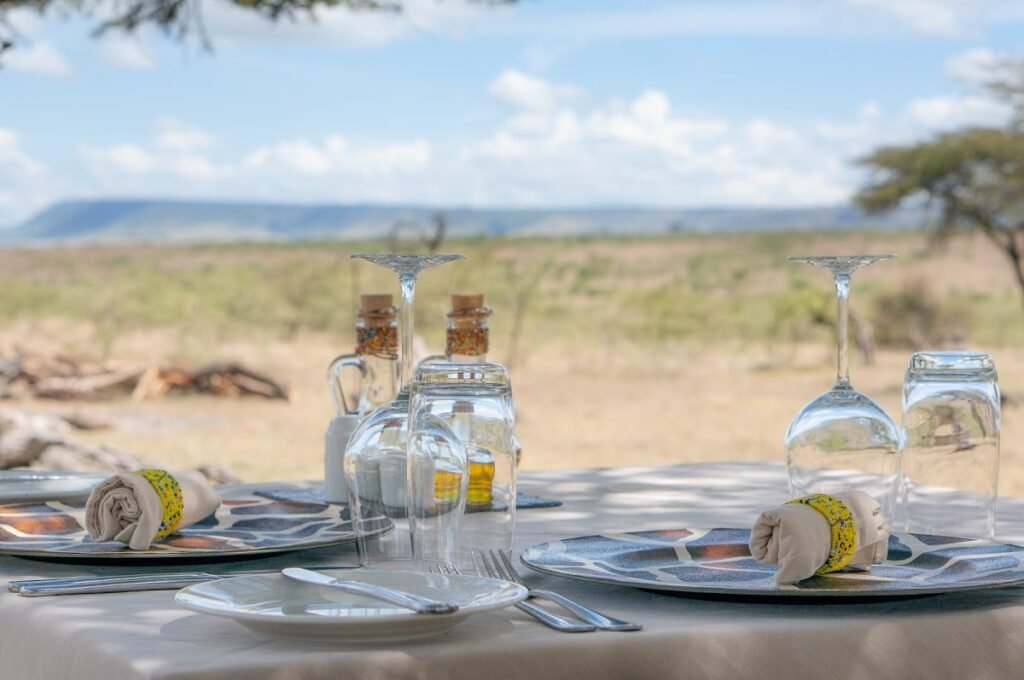 Kandili Camp outdoor table with glassware and a view across the savannah