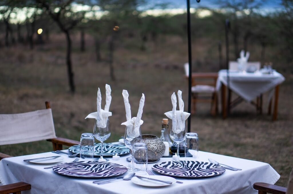 Outdoor dining table set with plates and folded napkins at Kandili Camp