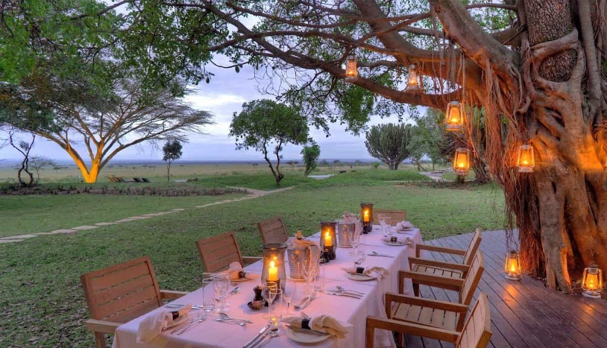 Outdoor dining at andBeyond Kichwa Tembo beneath trees beside the camp lawn