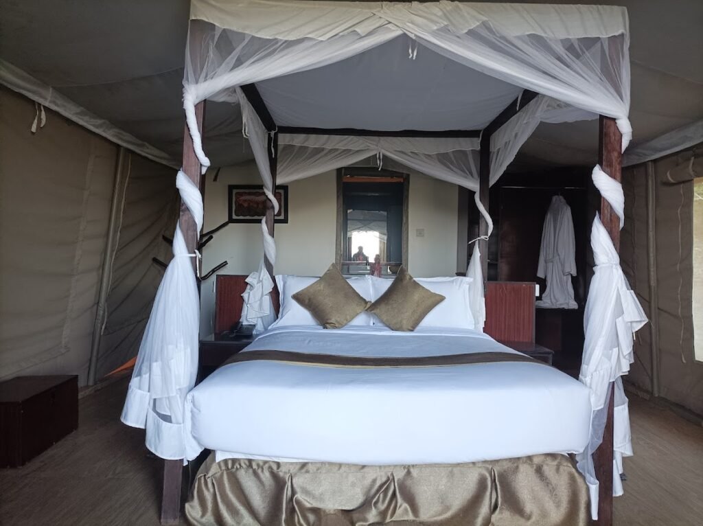 La Maison Royale Mara Camp double tent with a timber four-poster bed and white mosquito net