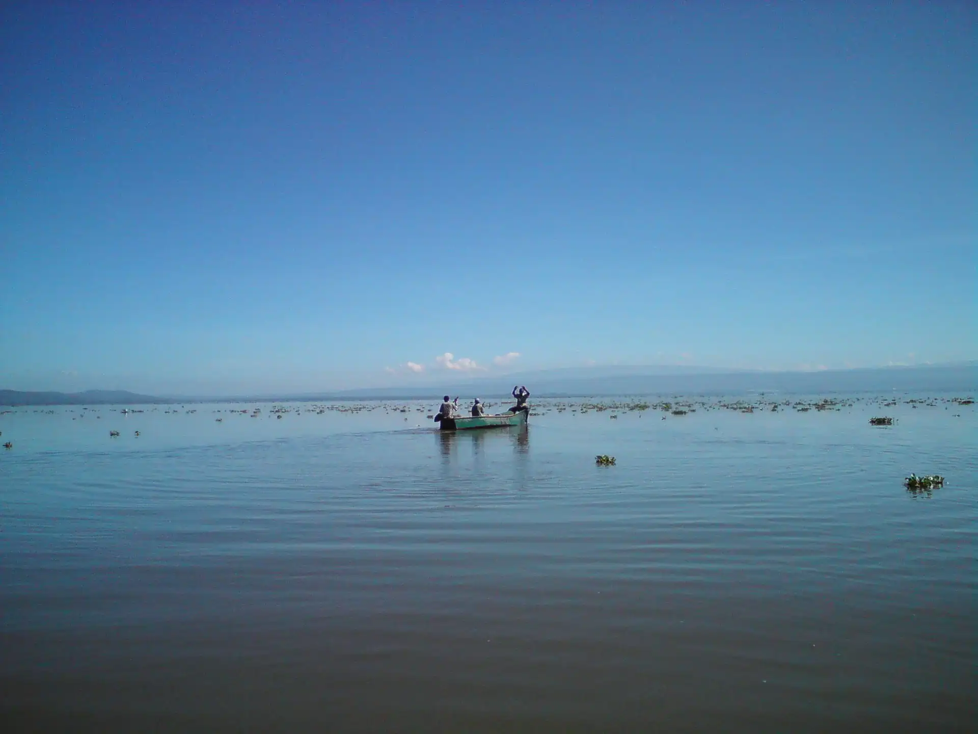 nakuru maasai mara safari: Fishermen in a boat on Lake Naivasha with distant hills