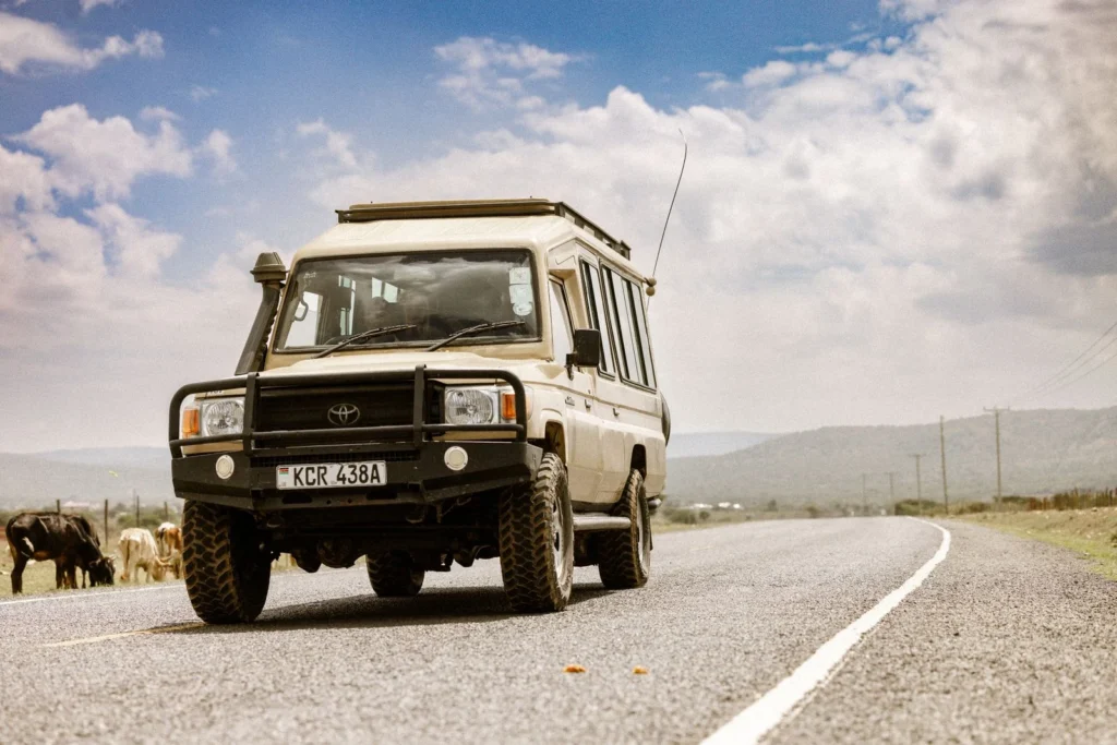 Land Cruiser Hire in Maasai Mara with a Professional Guide 5 Pop-up-roof Toyota Land Cruiser travelling on a Kenyan road