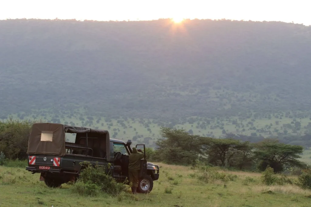 Land Cruiser Hire in Maasai Mara with a Professional Guide 4 Open-sided Toyota safari Land Cruiser overlooking green plains at sunset