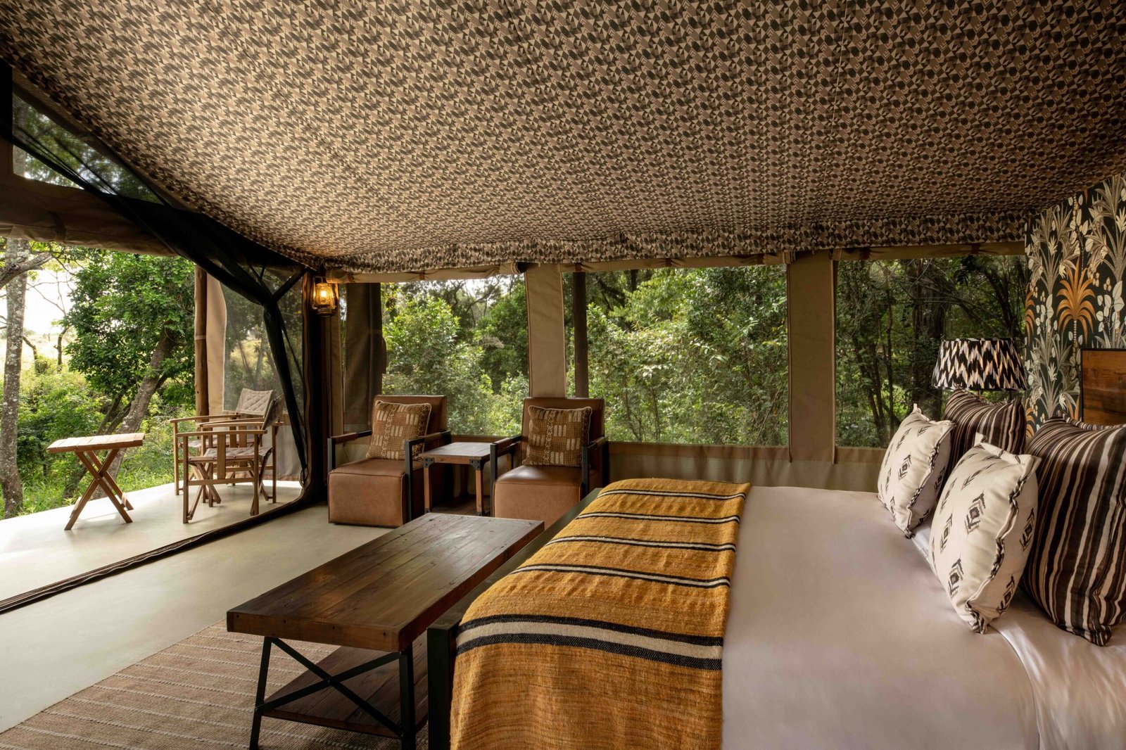 Botanical canvas tent interior with bed and lounge chairs at Lerai Safari Camp