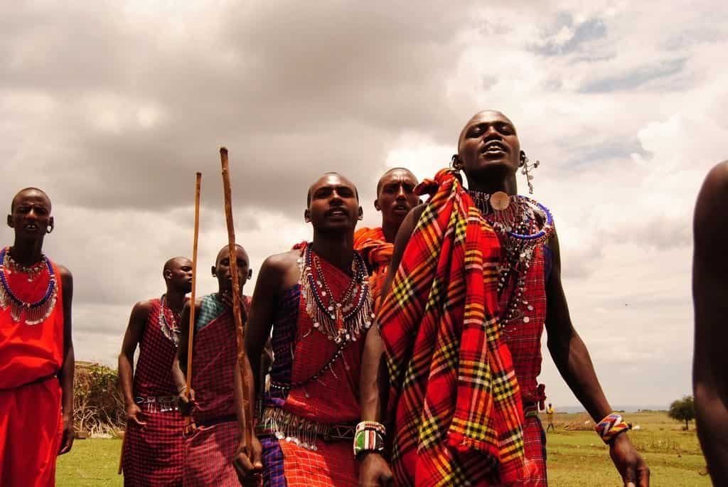 A thoughtful approach to a Maasai cultural visit 2 Maasai men wearing red cloth and beadwork during a dance in Kenya