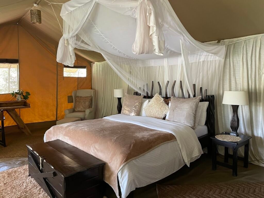Maasai Mara lodges and camps 29 Mara Crossings Camp canvas tent interior with mosquito net and striped headboard