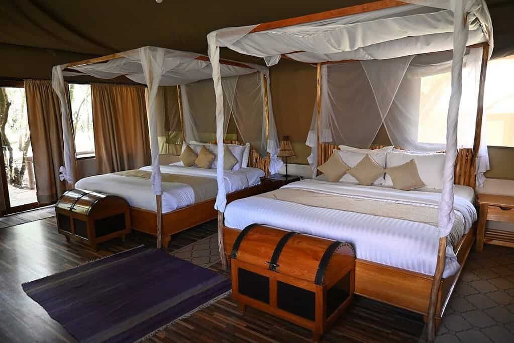 Self-catering accommodation in the Maasai Mara 3 Furnished safari tent bedroom with beds, mosquito nets and an outdoor seating view