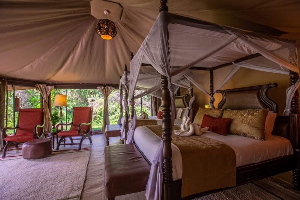 Mara Ngenche Safari Camp tent interior with wooden chairs beside the four-poster bed
