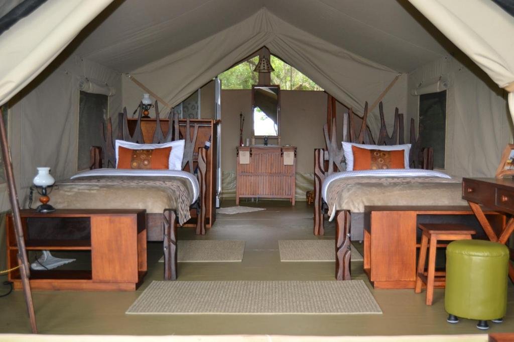 Twin timber beds beneath canvas at Exploreans Mara River Camp