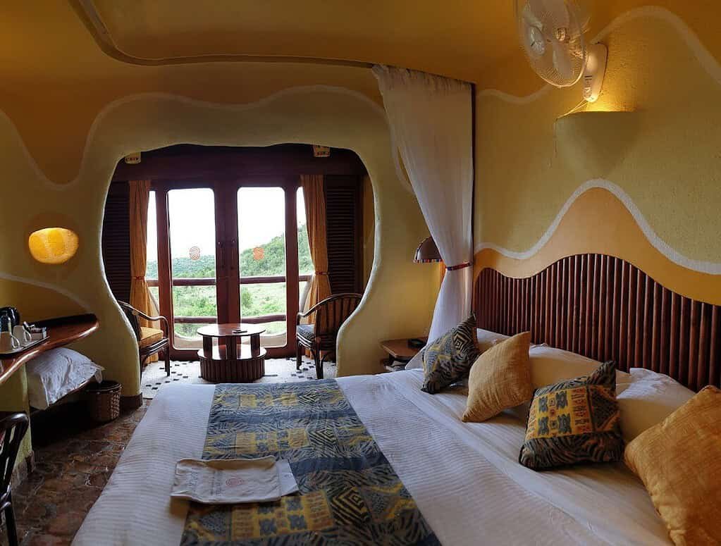Guest bedroom with curved walls and balcony doors at Mara Serena Safari Lodge