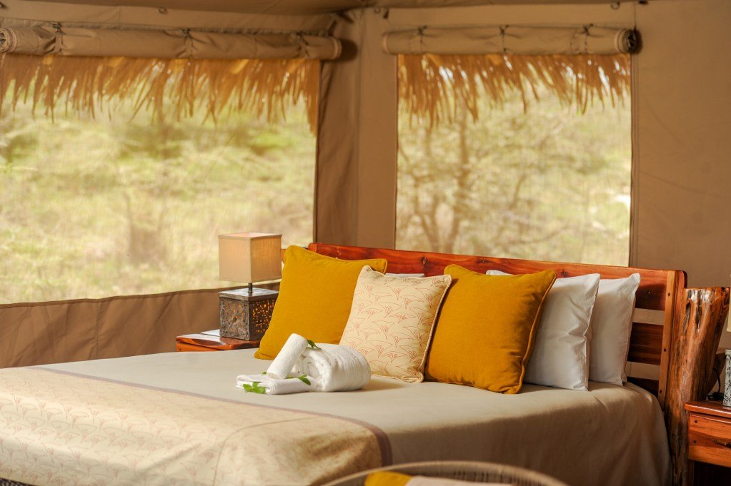 Mara Siana Camp king bedroom with bright cushions beneath canvas and thatch