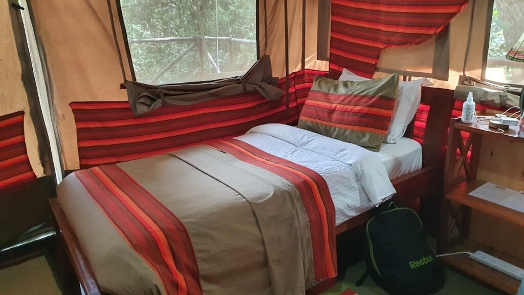Matira Bush Camp tent bed with red-striped textiles and canvas windows