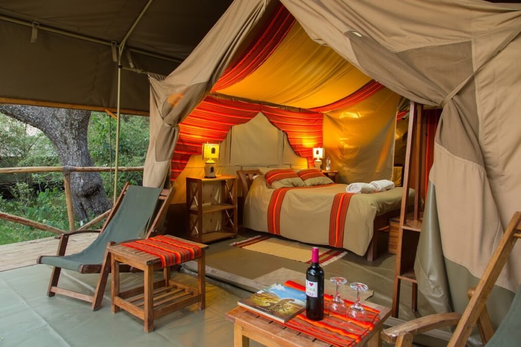 Maasai Mara lodges and camps 77 Matira Bush Camp canvas tent with red-striped bedding and a private veranda