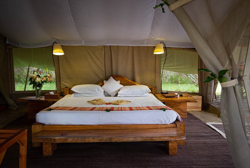 Naibor Camp canvas bedroom with wooden bed and mosquito net