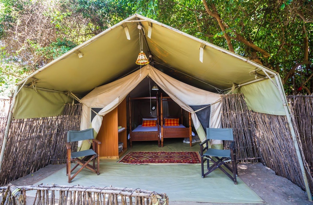 Oldarpoi Mara Camp canvas tent front with a timber bed frame and blue chairs