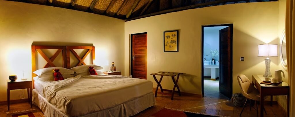 Ososian Mara Lodge bedroom with wooden cross-braced headboard and private bathroom