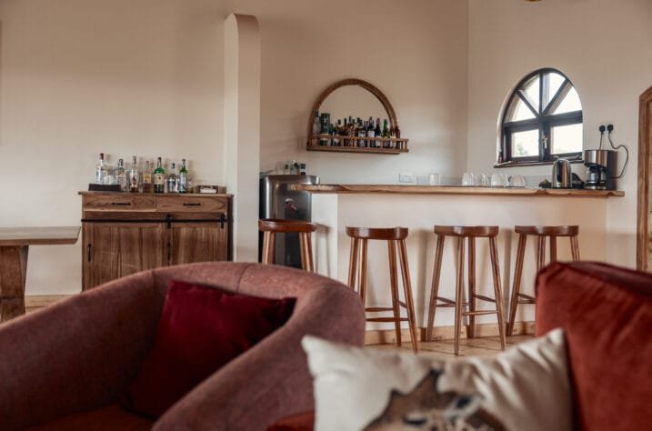 Porini Safari Cottages lounge and bar with wooden stools and arched window