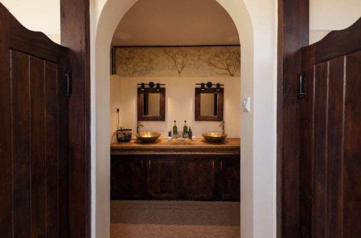 Porini Ol Kinyei Safari Cottages bathroom with twin basins and dark timber doors