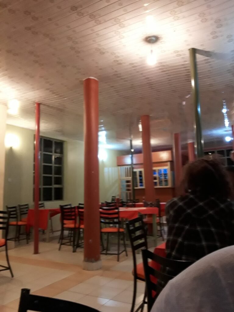 Restaurant seating at Rhino Tourist Camp with black chairs and red tablecloths