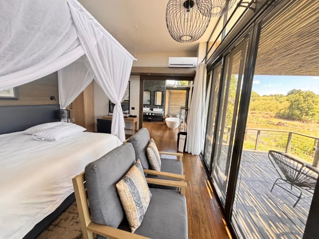 Sanctuary Olonana glass suite with canopied bed and river-facing sitting area