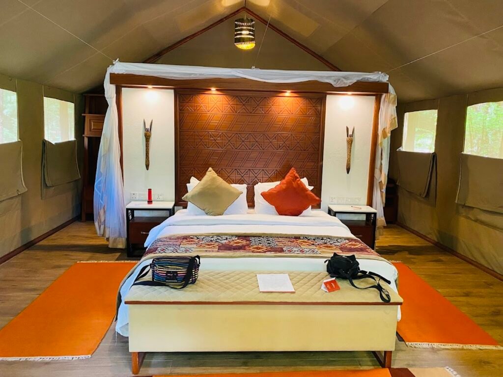 Maasai Mara lodges and camps 51 Sarova Mara Game Camp canvas tent bedroom with carved wooden headboard and mosquito net