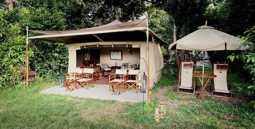 Sentinel Mara Camp canvas guest tent and outdoor seating beneath riverside trees