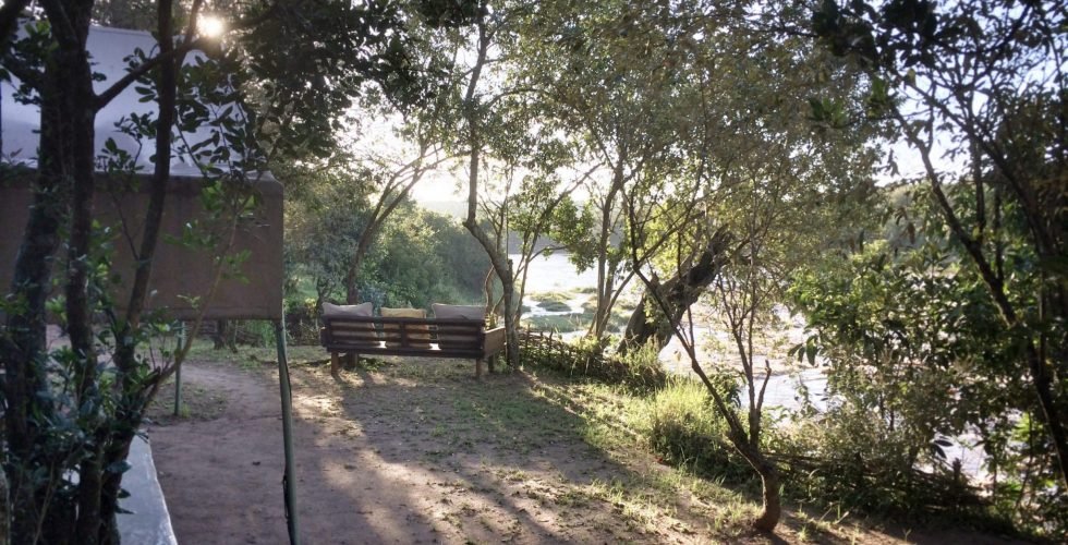 Maasai Mara lodges and camps 118 Nkorombo canvas tent and shaded seating beside the Mara River