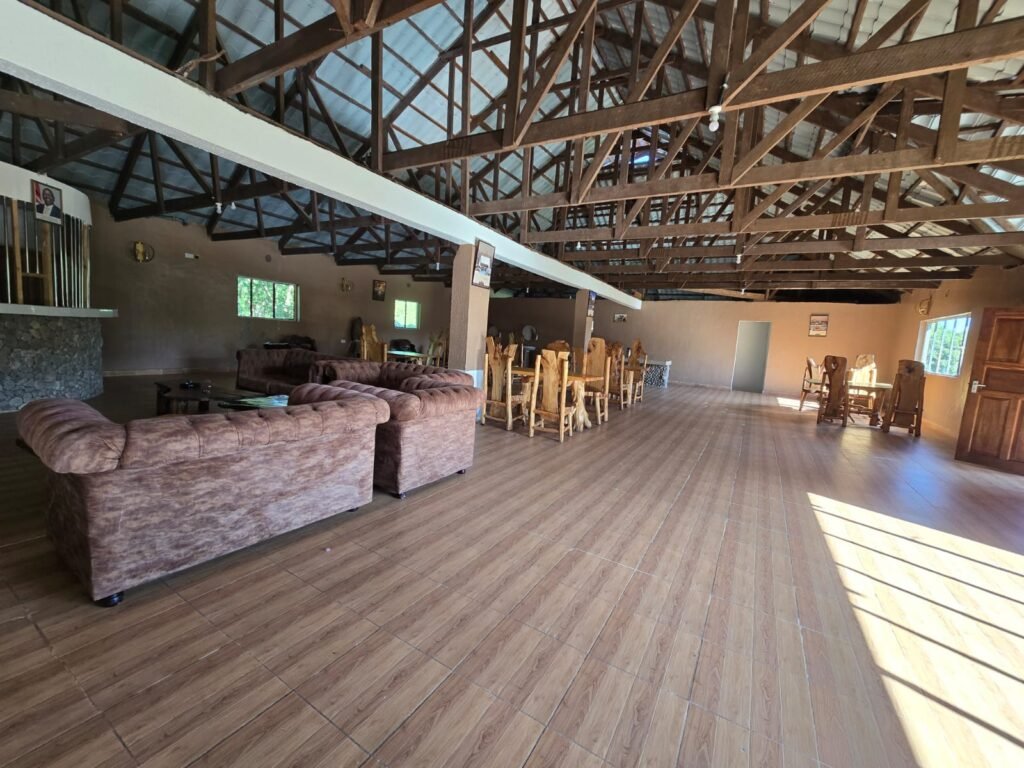 Wild Nest Mara Camp dining and lounge hall with timber trusses, wooden tables and upholstered seating